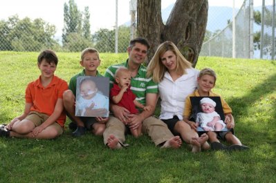 Family, sitting under tree, holding photos, facial defects
